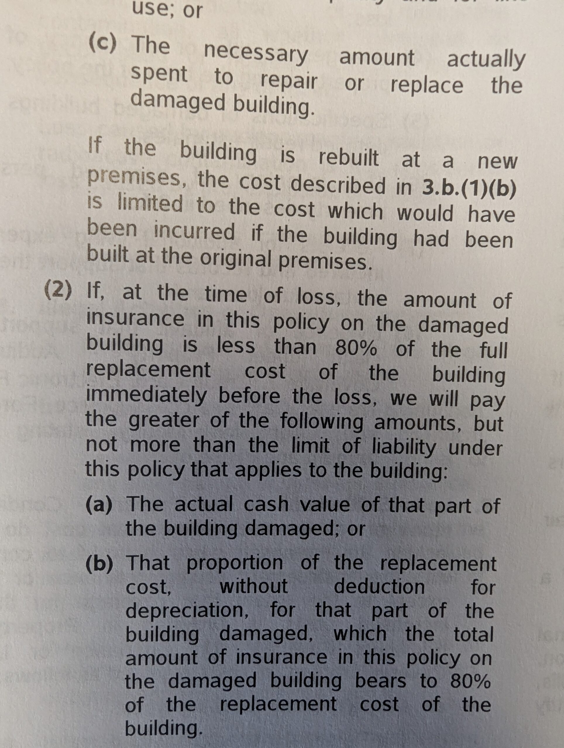 A close-up photo of a printed insurance policy document, focusing on sections about rebuilding costs and cash value in the event of building damage.